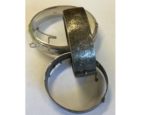 A silver hinged bangle together with two others. Approx. 80 grams. Est. £30 - £50.