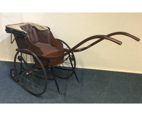 A vintage child's perambulator with spoked wheels and brass mounts, the seat in button-back leather. Est. £200 - £300.