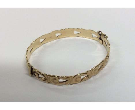 A 9 carat bangle with scroll decoration and concealed clasp. Approx. 13.7 grams. Est. £100 - £150.