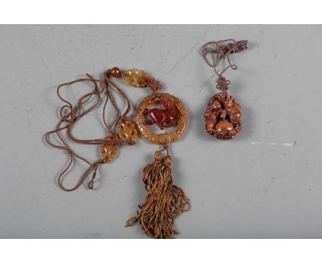 A carved agate pendant necklace, decorated horse, a carved fruitwood pendant, decorated two figures, a white metal Chinese ba