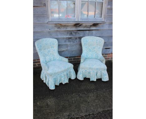 A pair of low seat nursing chairs, button upholstered in a blue floral fabric, on square supports 