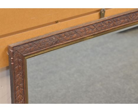 CARVED OAK WALL MIRROR, decorated with ribbon wrapped fruiting laurel in shallow relief, gilt slip, bevelled plate, 71 x 85cm
