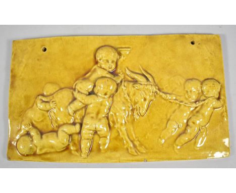 A Yellow Glazed Ceramic Plaque Depicting Cherubs and Goat, 28cm long 