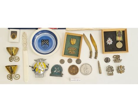 Collection of military badges, a military-style pocket compass, brass trench art, an AA car mascot, various small leather jew