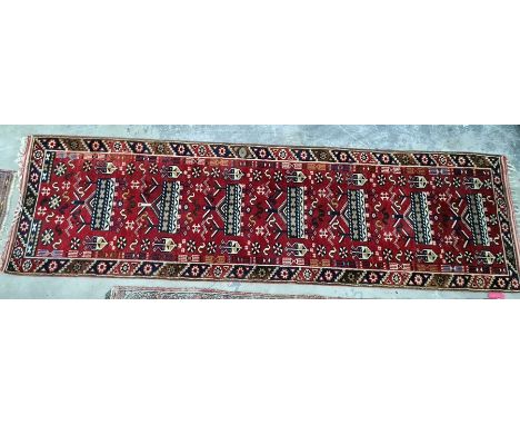 A Turkish runner red ground separate in white blue and yellow with single border; measurements 290/80cm 