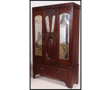 An Edwardian mahogany single wardrobe. The central mirror door with Art Nouveau panel work with short drawer to the base. Mat