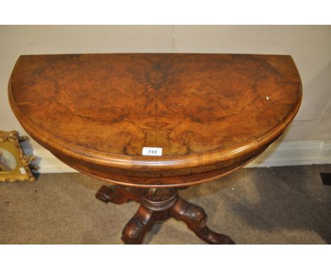 A Victorian figured mahogany bow front foldover card table,
with carved centre column and sabre leg base.