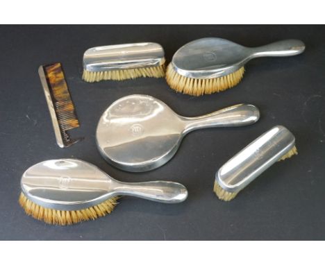 Matched silver backed dressing table set, comprising two hand brushes, hand mirror, comb and two clothes brushes, engraved in