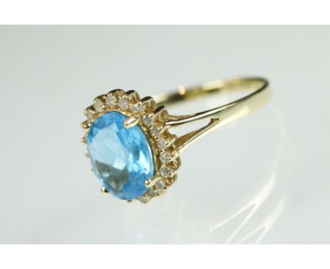 Topaz and diamond 14ct yellow gold cluster ring, the oval mixed cut blue topaz measuring approx 9mm x 7mm, claw set, small ro