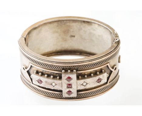 Victorian paste and seed pearl parcel gilt silver hinged bangle, the raised central section set with five pink paste stones a