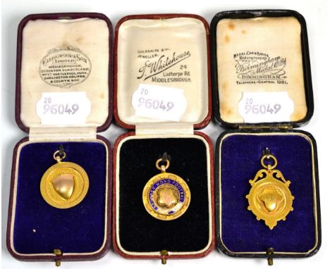 A gold and enamel football medal stamped 9ct and two 9 carat gold cricket medals (3)