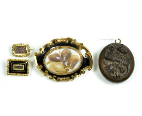 A mourning brooch, a central panel containing hairwork, to a black enamel border within a fancy scroll frame, with inscriptio