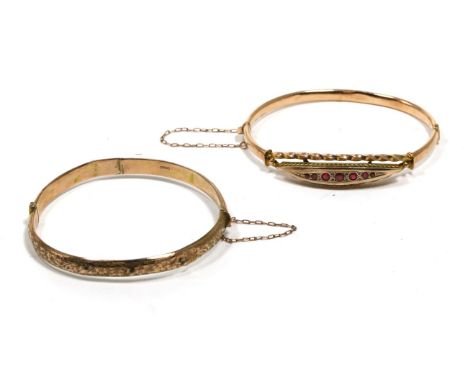 A late nineteenth century ruby bangle, graduated round cut rubies to a lozenge shaped plaque in a rope frame, to a plain hing