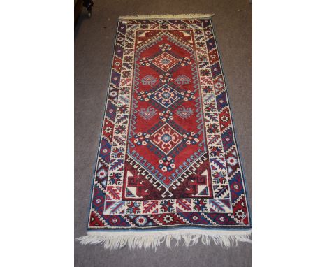 Caucasian small runner, double gull border, central panel of three lozenges, mainly red and blue field, 183 x 80cm