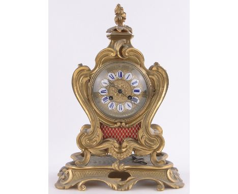 A 19th century French gilt bronze cased mantel clock on stand in Rococo style,with elaborate acanthus scroll case & enamel nu