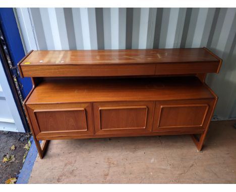 A mid 20th century McIntosh teak mid height sideboard with three drawers, over a shelf and three doors on cut out ends, 102cm