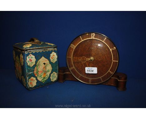 A battery operated German made Mantle Clock and a tin Tea Caddy with oriental decoration.