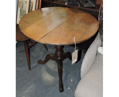 An early 19th Century oak tea table with circular tilt top on turned pillar and cabriole tripod.