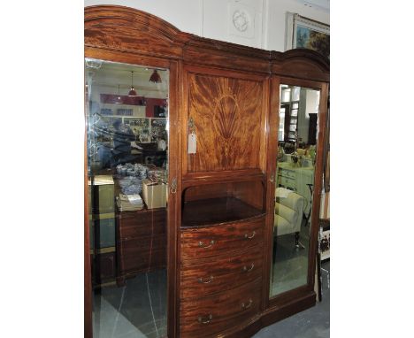 An Edwardian marquetry inlaid mahogany wardrobe with central cupboard over three bowed drawers flanked by mirrored wing cupbo