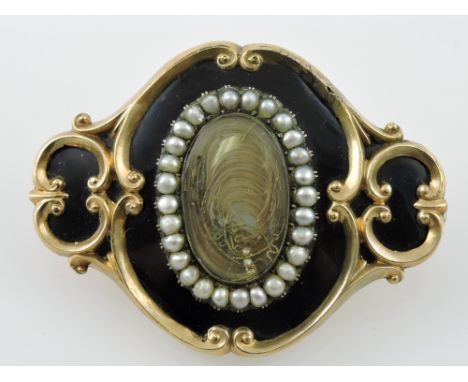 A Victorian yellow metal, enamel and seed pearl memorial brooch, centred by an oval mount of hair, the reverse inscribed 'Ann
