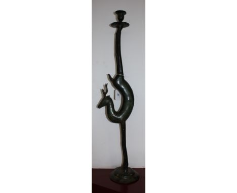A bronzed metal candlestick modelled as a stylised stag, the sconce supported by the hind quarters, H. 75cm.