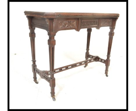 A early 20th Century Edwardian mahogany card table being raised on square carved tapering legs with brown ceramic castors, un