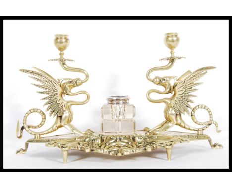 A 19th Century cast brass desk tidy / inkstand, with dual griffin sconces to both sides having glass red eyes and glass inkwe
