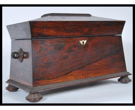 A 19th Century rosewood tea caddy of sarcophagus form having mother of pearl inlay to the lid, raised on bun feet with ring h