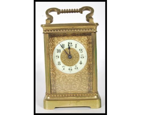 A early 20th Century brass French carriage clock having white enamel chapter ring with arabic numerals and floral relief deco