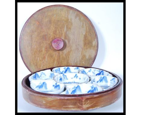 A 20th Century Chinese lazy Susan consisting of a round lidded wooden box with rotating base below having fitted ceramic hord
