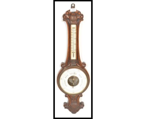 An early to mid 20th Century oak cased banjo aneroid barometer, white enamel dial below thermometer. Measures 80cm high