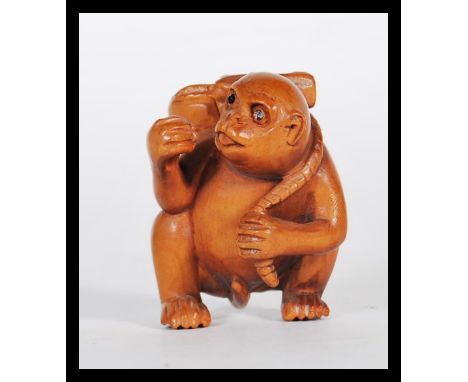 A 20th Century Japanese carved wood netsuke in the form of a monkey carrying a fruit to its back. Signed to the back.&nbsp;