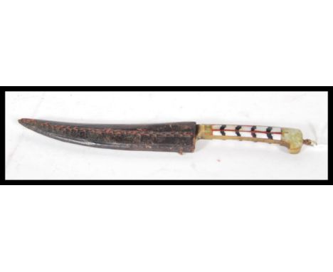 A early 20th Century dagger/ knife, having brass, jade and mother of pearl decorated handle with shaped blade, within leather