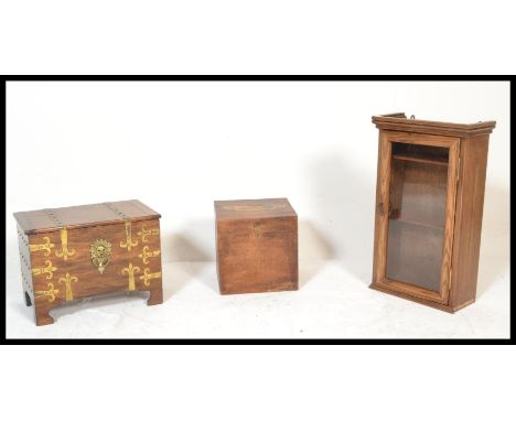 A 20th Century elm glazed fronted hanging cabinet together with a brass bound chest having a hinged top raised on bracket sup