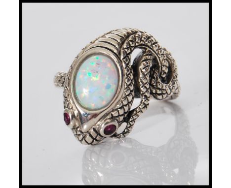 A silver ring in the form of a snake having ruby eyes and opalite cabochon to head, the snake body twisting into the ring its