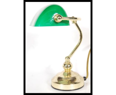 A vintage 20th century bankers desk lamp having an adjustable green glass shade raised on a brass support and good brass base