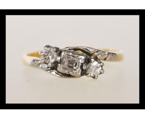 A mid 20th Century stamped 18ct gold and platinum ring set with a central square cut diamond flanked by two round cut diamond