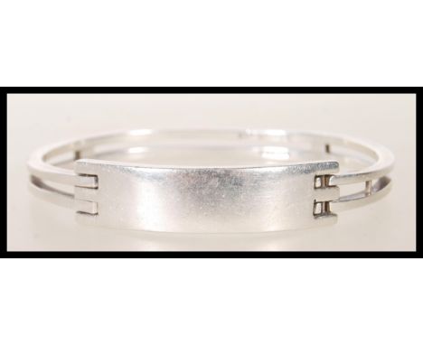 A stamped 925 silver bangle bracelet having square bars culminating in a square geometric clasp. Weight 39.8g.