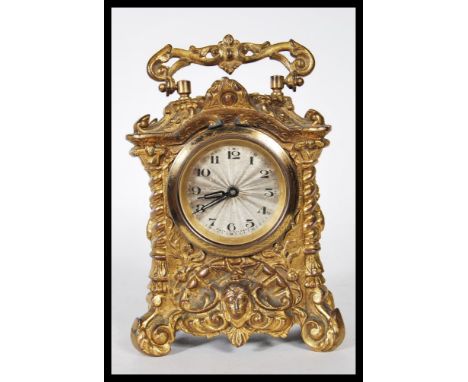 An early 20th Century gilt cast carriage clock, the clock cast in relief in the rococo taste having a silver machined dial, w