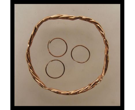 A 9ct gold rope twist slave bangle being stamped 375 together with 3 9ct gold marked creole earrings. Bangle measures 2.5" di