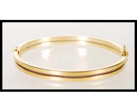A stamped 9ct gold bangle bracelet having a hinge opening constructed from two bands with a catch to one side. Stamped 9k Ita