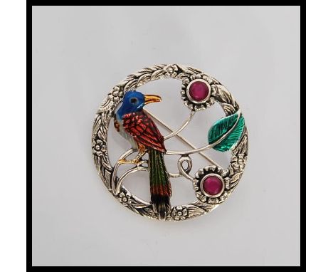 A circular silver and enamel set brooch / pendant in the form of a tropical bird having floral decoration. Stamped sterling t