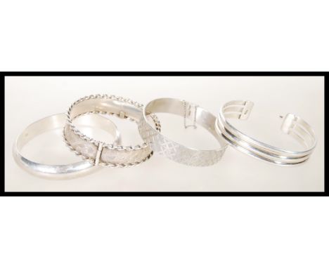 A selection of four silver bangle bracelets to include a hallmarked bangle with graved decoration and twisted borders (hallma