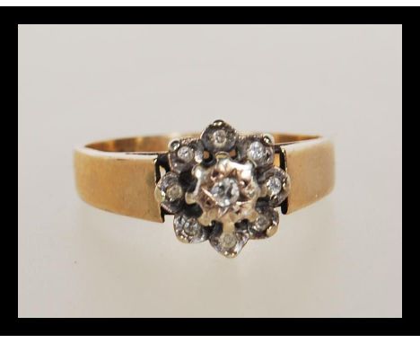 A 9ct gold London hallmarked cluster ring adorned with approx 0.25cts of diamonds in a flower head setting. Size P / Weight 3