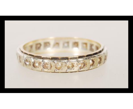 A stamped 9ct gold two tone eternity ring set with white stones to the band. Weight 3.1g. Size S.