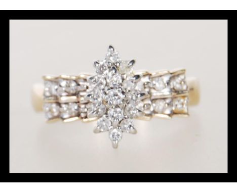 A hallmarked 9ct gold ring having a cluster of white stones to head with stepped shoulders set with further white accent ston