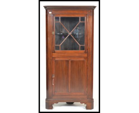 An early 20th Century mahogany Edwardian corner cabinet, glazed astral glazed door with shelved interior over panel door rais