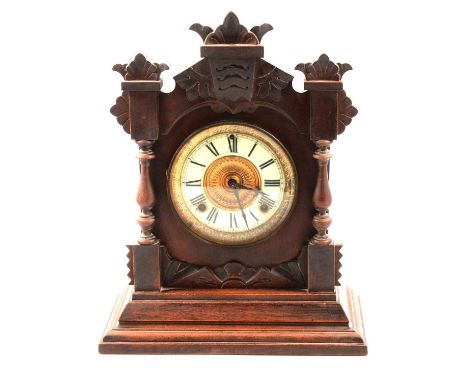 An Ansonia twin train mantel clock, carved walnut case, cream enamel chapter ring with Roman numerals, the movement striking 