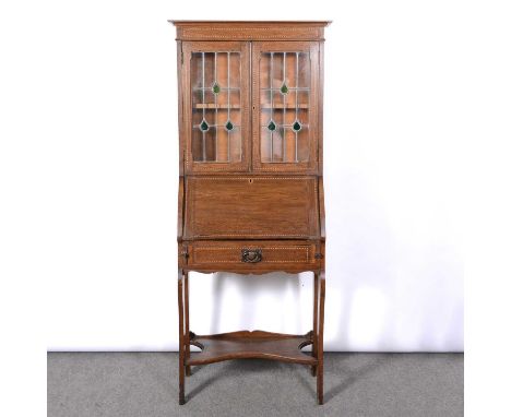 Edwardian oak bureau bookcase, boxwood and ebony stringing throughtou, the upper section with stained leaded glass doors ancl