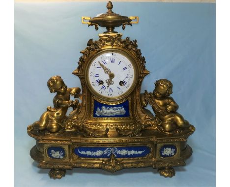 A French ormolu mantel clock decorated with putt, inset porcelain panels, movement by Japy Freres, 32 cm high, hardwood base 